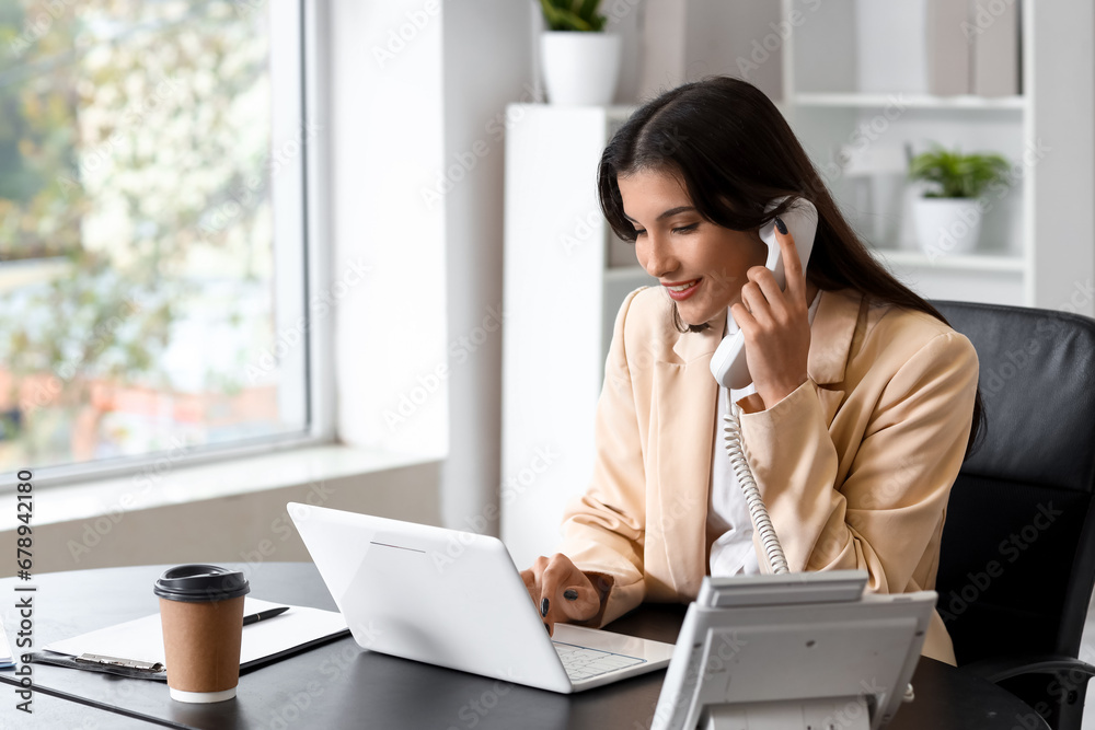 Wall mural beautiful businesswoman talking by telephone at table in office