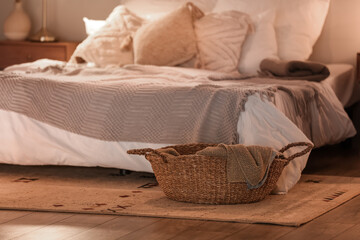 Fototapeta na wymiar Wicker basket with plaid in bedroom