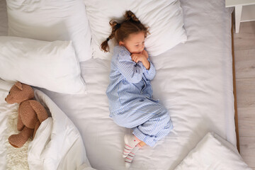 Frozen little girl sleeping on bed, top view