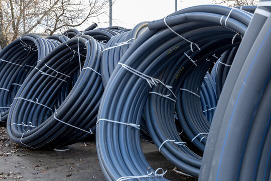 Coils of black polyethylene pipes for laying high voltage electrical cables underground at a construction site. Electrical insulation