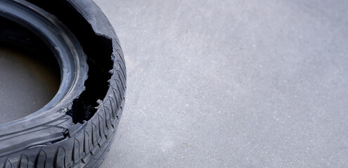 A fragment of an old torn rubber of a car tire on a gray asphalt background with a copy space. The...