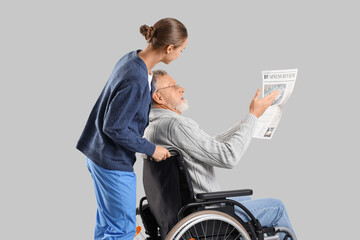 Obraz premium Senior man in wheelchair with newspaper and nurse on light background