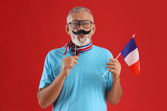 Senior man with paper mustache and flag of France on red background