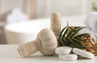 Fototapeta na wymiar Spa composition. Herbal bags, stones and palm leaves on white table indoors, closeup