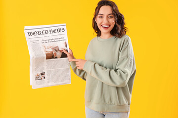 Young woman with newspaper on yellow background - obrazy, fototapety, plakaty