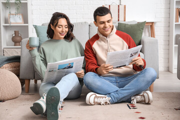 Young couple with newspapers at home