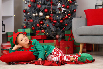 Cute little girl in elf costume lying at home on Christmas eve