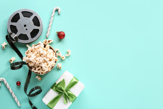 Bucket of popcorn with film reel, candy canes and gift box on turquoise background