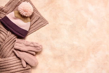 Pair of knitted mittens with warm hat and scarf on beige grunge background