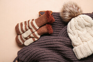 Winter mittens with warm hat and scarf on beige background