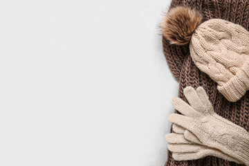 Knitted gloves with warm scarf and hat on white grunge background