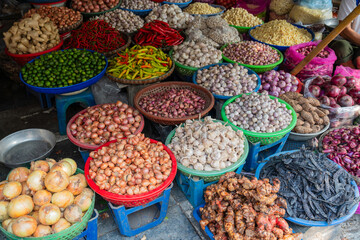 Baskets of different types of dried fruit, herbs, vegetables in an outdoor market on Hanoi street