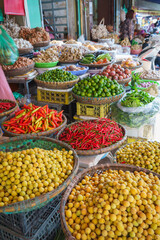 Baskets of different types of dried fruit, herbs, vegetables in an outdoor market on Hanoi street