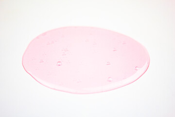 Pink liquid on a white background, transparent pink drop, gel. Concept of cosmetics, science, medicine.