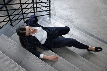 Woman fallen down stairs suffering from pain in back, above view