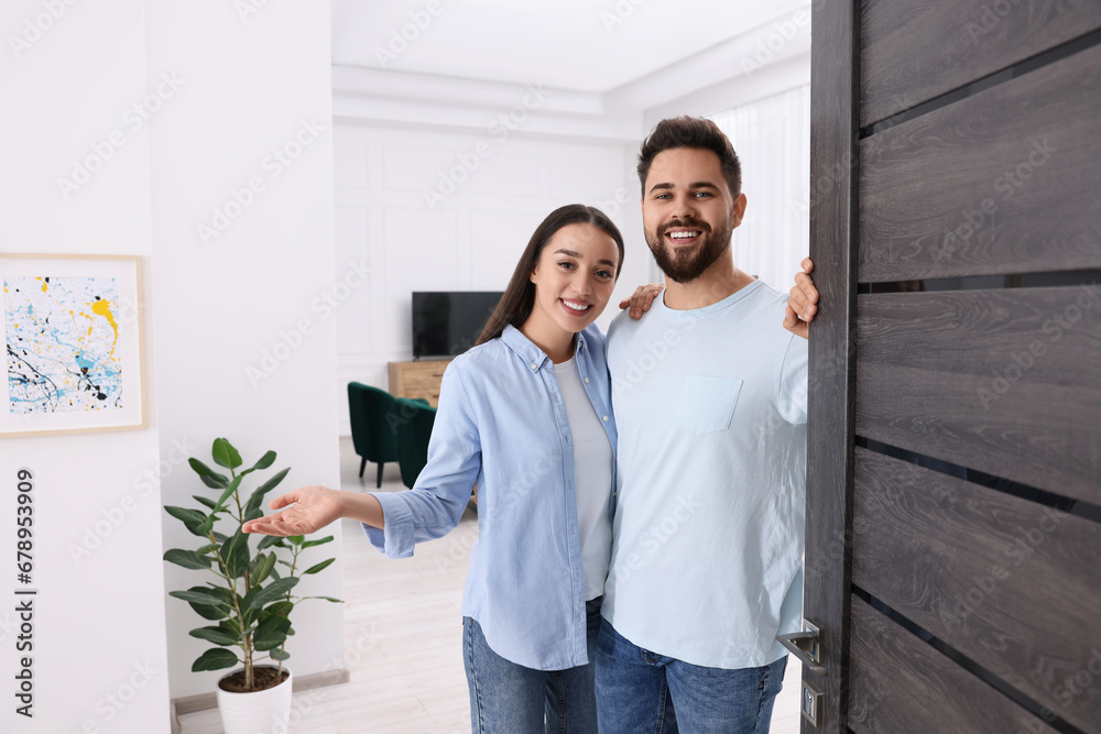 Wall mural Happy couple welcoming near door. Invitation to come indoors