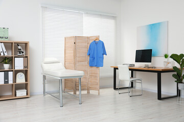 Modern medical office with doctor's workplace and examination table in clinic