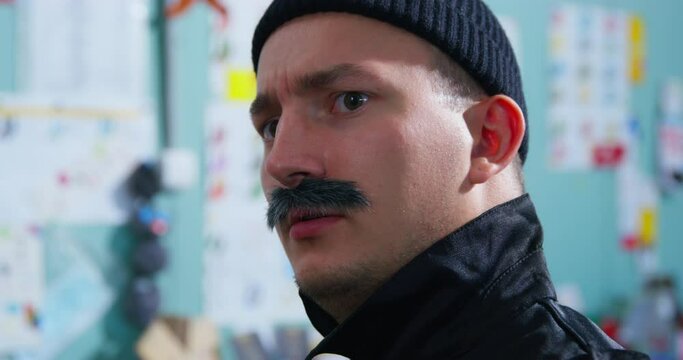 Profile of man in black tight hat, with mustache of criminal appearance, looks carefully, tracks down victim, plans robbery slow-witted security guard checkpoint scans, examines, looks with suspicion