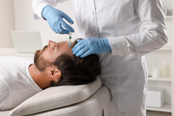 Trichologist giving injection to patient in clinic, closeup