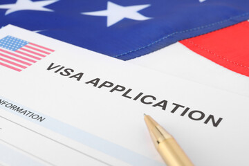 Immigration to USA. Visa application form and pen on flag, closeup