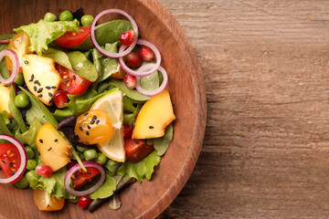 Delicious salad with peach, green peas and vegetables in bowl on wooden table, top view. Space for text