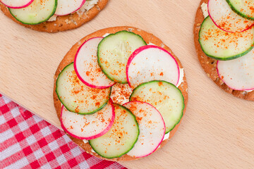 Light Breakfast or Diet Eating - Crispy Cracker Sandwich with Cream Cheese, Fresh Cucumber and Radish on Wooden Cooking Board on Magenta Background