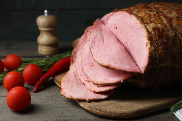 Delicious baked ham, tomatoes, chili pepper and rosemary on grey wooden table, closeup