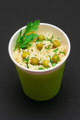Prepared Instant Noodles with Green Pea and Greens in Green Cup on Black Background. Quick Lunch or Unhealthy Fast Food