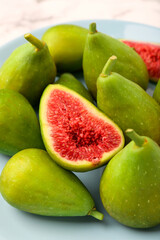 Cut and whole green figs on light blue plate, closeup
