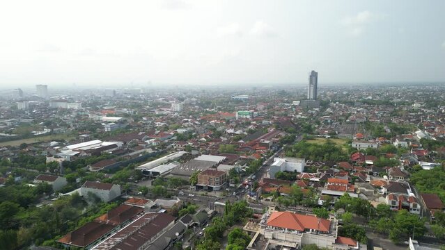 Aerial view of Solo Surakarta City with dense crowded buildings development in morning sunlight with smog or fog. Population density is displacing agricultural land and forests. Air Pollution