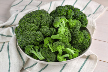 Bowl of fresh raw broccoli on white wooden table