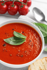 Delicious tomato cream soup in bowl served on table, closeup