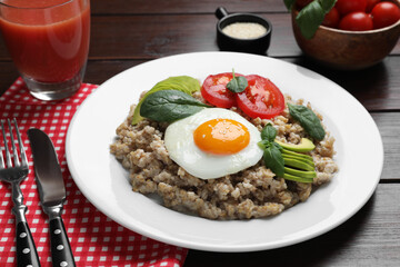 Delicious boiled oatmeal with fried egg, tomato and avocado served on wooden table