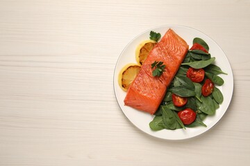 Tasty grilled salmon with basil, tomatoes and lemon on white wooden table, top view. Space for text