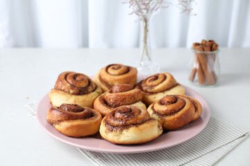 Many tasty cinnamon rolls on white table