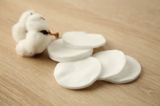 Cotton pads and flower on wooden table, closeup