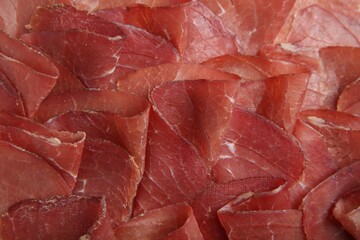 Slices of tasty bresaola as background, top view