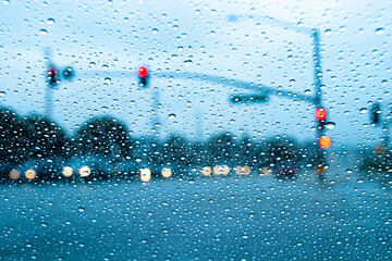 Raindrops in focus on a windshield. with an intersection diffused in the background