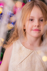 A beautiful elegant girl near the Christmas tree in the New Year. Holiday. New Year. The child is a model.