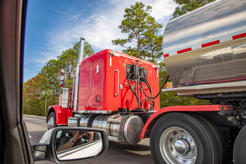 american large red truck at the highway overtaken by a prvate car,