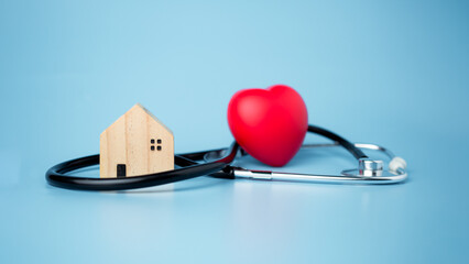 Concept of health insurance and medical welfare, small wooden house and red heart with stethoscope...