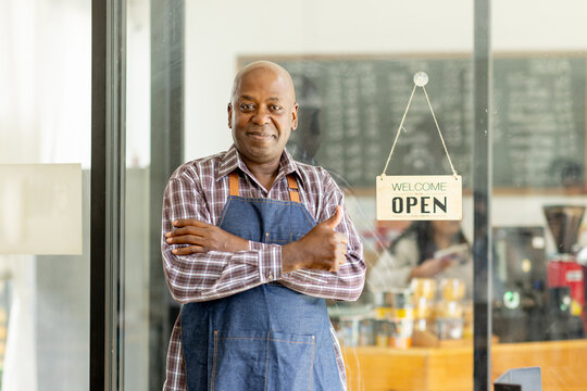 Financial freedom of small business Shot of a cheerful senior man smiling happily holding up an open sign posing at his own cafe in front of the door senior male standing his small business sme.