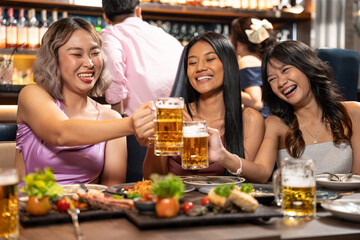 Group of People Holding Beer and Cheer in Restaurant. They Enjoying with Night Party Together. Party, Lifestyle, Happiness, Cheerful and Celebration concept. 