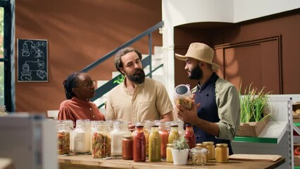 Owner offers fresh produce samples to clients shopping for groceries, diverse couple looking to buy potatoes and pantry supplies for healthy meal. Local eco storekeeper recommending goods. - Powered by Adobe