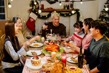 Happy and Cheerful group of extended Asian family has a toast and cheer during Christmas dinner at...