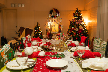 Empty traditional Christmas dinner table inside decorated living room with holiday garlands and dinnerware. Interior of traditional and authentic season cozy setting celebrating religious event.