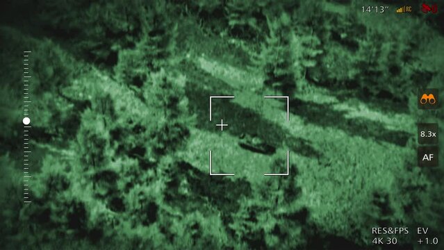 Night vision military drone flying above the battlefield. Night vision military drone looking for enemy vehicles in the area. Night vision military drone striking the enemy tank with explosive weapon.