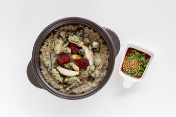 Korean food. Oyster hot stone pot rice with mushroom, jujube, sliced radish and soy sauce. Isolated on white background. Top view.
