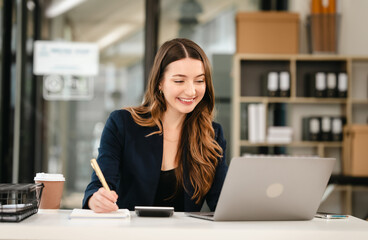 Attractive professional caucasian businesswoman working on her laptop, likely in an office setting, Balance Sheet, Accounting of Owners Equity, Cash Receipts Journal, Liabilities, Idle Capacity