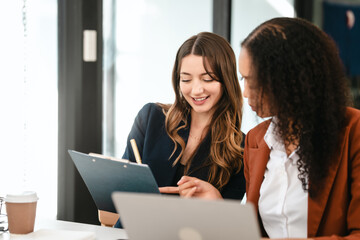 Two professional caucasian with african american businesswoman friends collaboration, working together at office, using laptop, Generally accepted audit standards, Earnings before interest and taxes